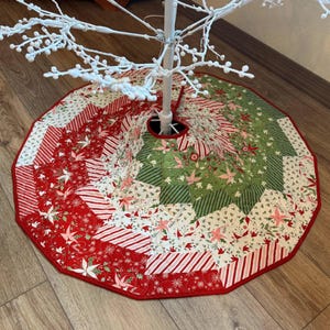 May include: A circular Christmas tree skirt featuring a patchwork design of red, green, and white fabric segments. The pattern includes floral motifs, poinsettias, and striped sections arranged in a radiating starburst layout with a central opening.