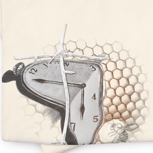 Puede incluir: Camiseta color crema con un diseño surrealista. Presenta un reloj derritiéndose con números romanos, un patrón de panal y una abeja. El diseño está en tonos de gris y marrón.