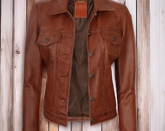 May include: A brown leather jacket featuring a classic collar, long sleeves, and a button-down front closure. The jacket includes two chest pockets with buttoned flaps and a smooth, dark brown interior lining with a rectangular brand label at the neck.