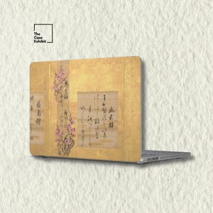 May include: A laptop skin featuring a gold-toned background with a vertical branch of pink cherry blossoms and black Japanese calligraphy script. The design mimics a traditional folding screen, incorporating elegant floral art and text.