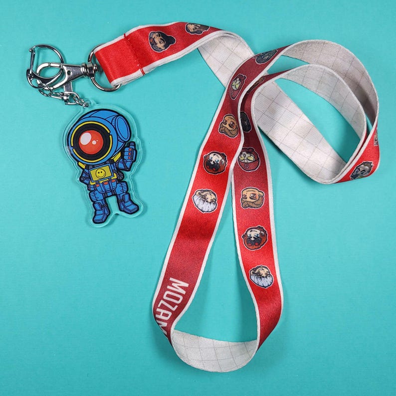 May include: A red and white lanyard with a grid pattern and cartoon characters printed on it. The lanyard has a silver key chain attached to it with a blue and yellow cartoon robot charm.