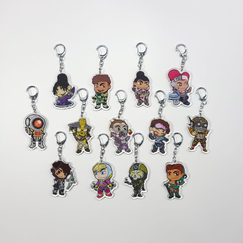 May include: A set of 12 colourful character keychains featuring characters from the video game Apex Legends. The keychains are made of clear acrylic and feature a variety of characters, including Bloodhound, Lifeline, and Mirage.