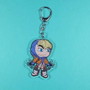 Puede incluir: Un llavero con un personaje de anime azul y naranja con cabello rubio y ojos azules. El personaje lleva una chaqueta con capucha azul y pantalones naranjas. El llavero est&aacute; unido a un anillo de metal plateado.