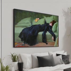 May include: A painting of a woman in a black dress lying on a green couch. She is holding a book in her hand and her eyes are closed. The painting is framed in black.