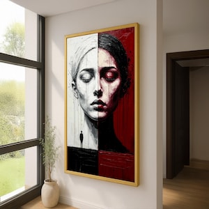 Könnte beinhalten: Ein gerahmtes Kunstwerk, das das Gesicht einer Frau vertikal geteilt darstellt. Eine Seite ist schwarz-weiß, die andere rot. Die linke Seite zeigt eine Frau mit weißer Kopfbedeckung, die rechte Seite hat einen roten Hintergrund. Eine kleine Figur steht auf einer schwarzen Oberfläche.