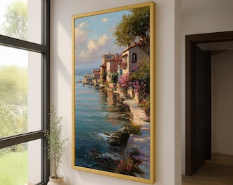 Pode incluir: Pintura emoldurada de uma paisagem costeira com edifícios à beira-mar. A obra de arte, numa moldura dourada, apresenta uma paleta vibrante de azuis, rosas e verdes, criando uma atmosfera serena. Pendurada numa parede branca.