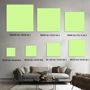 K&ouml;nnte beinhalten: Darstellung von sieben quadratischen, hellgr&uuml;nen Leinwandkunstwerken in verschiedenen Gr&ouml;&szlig;en, von 40x40 cm bis 100x100 cm (16x16 Zoll bis 40x40 Zoll). Jede Leinwand ist mit ihren Abmessungen in cm und Zoll beschriftet. Die Kunst wird &uuml;ber einem Sofa ausgestellt.