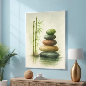 Puede incluir: Una impresión en acuarela enmarcada representa una pila de piedras lisas y coloridas equilibradas cerca de tallos de bambú. Las piedras varían en color de verde a marrón, y el bambú es de un verde vibrante. La obra de arte evoca una sensación de paz y tranquilidad.