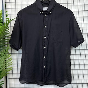 May include: A black short-sleeved button-down shirt with a pocket on the left side. The shirt has a white label with the word "ETON" on it.