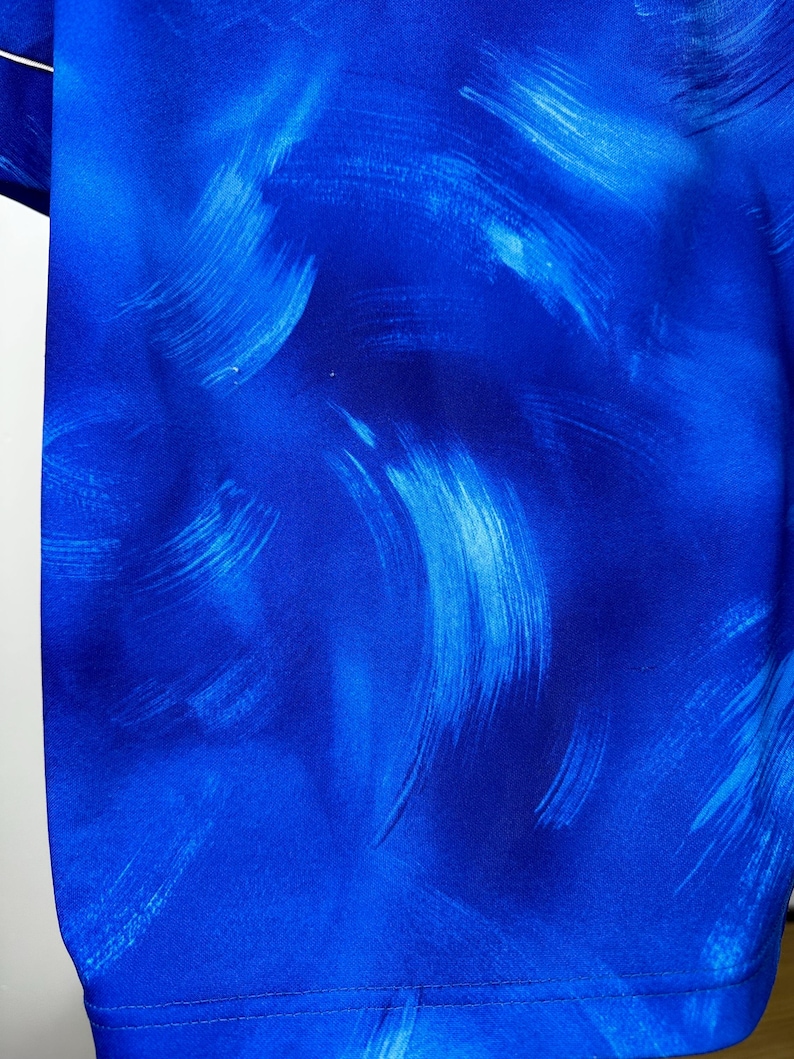 May include: Blue fabric with a white abstract brushstroke pattern.