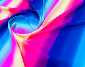 May include: A close-up of a colorful fabric with horizontal stripes in shades of pink, blue, and yellow. The fabric is soft and flowing, creating a sense of movement.