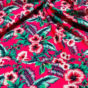 May include: Pink fabric with a tropical print featuring white hibiscus flowers and green leaves.