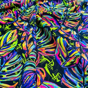 May include: A black fabric with a colorful tropical leaf print. The leaves are painted in bright neon colors, including pink, green, blue, and yellow. The fabric has a textured, slightly shiny surface.