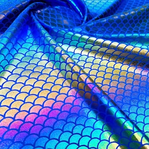 Puede incluir: Tela azul iridiscente con un patrón de escamas de sirena. Las escamas son un degradado de colores, incluyendo azul, verde y dorado.
