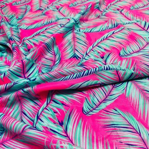 May include: Pink fabric with a tropical leaf pattern in shades of green and blue.