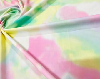 May include: A close-up of a soft, white fabric with a tie-dye pattern in shades of pink, yellow, and green.