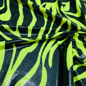 Puede incluir: Tela de estampado de cebra negra y verde neón con un acabado brillante y texturizado.