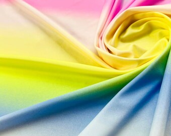 May include: A close-up of a colorful ombre fabric with a gradient of pink, yellow, green, and blue. The fabric is soft and smooth, and it is perfect for sewing projects or crafts.