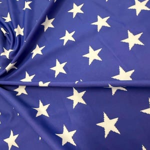 Puede incluir: Una tela azul con un patrón repetitivo de estrellas blancas de cinco puntas. El material está drapeado, creando pliegues suaves que distorsionan la alineación del estampado de estrellas en la superficie del textil, con un esquema de color uniforme.