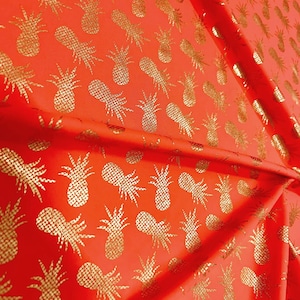 Puede incluir: Tela roja con estampado de piña dorada. La tela es texturizada y tiene un ligero brillo.