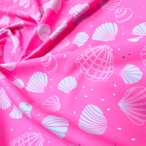 Puede incluir: Tela rosa con un patrón de conchas blancas. La tela tiene un brillo sutil.