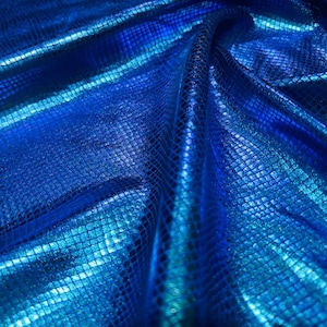 Könnte beinhalten: Nahaufnahme eines leuchtend blauen Stoffes mit einem strukturierten, schuppenartigen Muster. Das Material hat eine glänzende, irisierende Qualität, wobei Glanzlichter und Schatten Tiefe erzeugen. Der Stoff wird wahrscheinlich für Kleidung oder Dekorationszwecke verwendet.