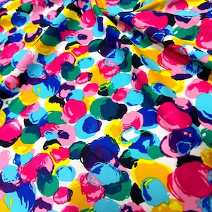 Puede incluir: Tela blanca con un estampado abstracto de colores de círculos superpuestos en tonos de rosa, azul, amarillo, verde y morado.