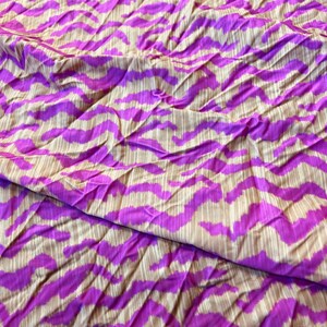 May include: Purple and beige fabric with a wavy, abstract pattern. The fabric is wrinkled and has a soft, silky texture.