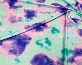 May include: Abstract tie-dye fabric with pink, blue and green colours. The fabric has a soft, flowing texture.
