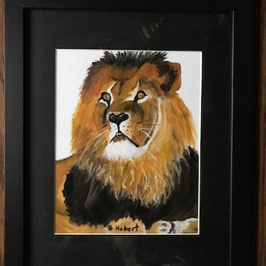 May include: A framed painting of a lion. The lion has a golden mane, brown eyes, and a black nose. The painting is signed "B Hubert" in the bottom left corner. The frame is black.