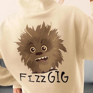 May include: Cream-colored hoodie featuring a cartoon monster graphic on the back with the word "FizzGig" in black. The monster is brown with large eyes and a toothy grin. The hoodie has a hood and long sleeves.