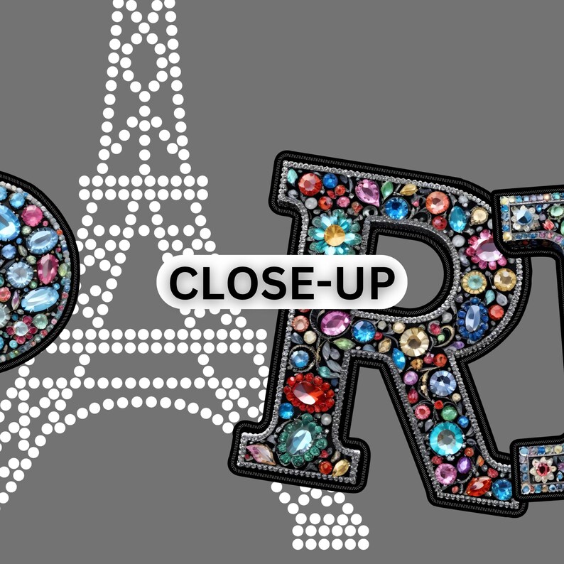 May include: Close-up of a decorative letter "R" embellished with colorful gemstones. The letter is outlined in black and set against a gray background. A white Eiffel Tower outline and the text "CLOSE-UP" are also visible.