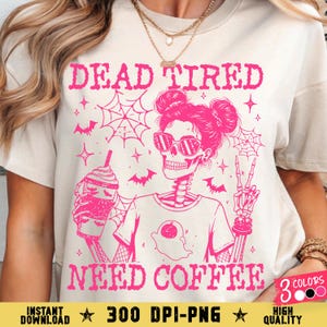 Pode incluir: Camiseta bege com um gráfico rosa de um esqueleto usando óculos de sol, segurando uma bebida de café e fazendo um sinal de paz. O texto "DEAD TIRED NEED COFFEE" está acima e abaixo do gráfico. O texto adicional diz "300 DPI-PNG" e "HIGH QUALITY".