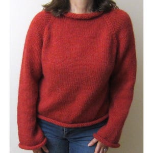 Puede incluir: Un su&eacute;ter rojo tejido con cuello redondo y mangas largas. El su&eacute;ter tiene pu&ntilde;os y dobladillo acanalados. Las mangas ragl&aacute;n est&aacute;n unidas al cuerpo del su&eacute;ter. El su&eacute;ter est&aacute; hecho de un hilo suave y texturizado.