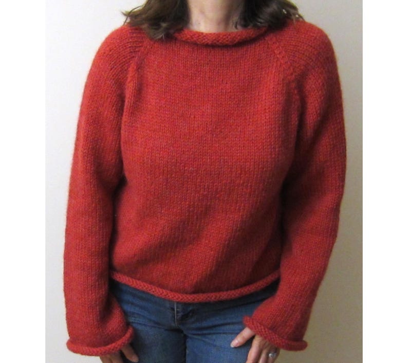 Puede incluir: Un su&eacute;ter rojo tejido con cuello redondo y mangas largas. El su&eacute;ter tiene pu&ntilde;os y dobladillo acanalados. Las mangas ragl&aacute;n est&aacute;n unidas al cuerpo del su&eacute;ter. El su&eacute;ter est&aacute; hecho de un hilo suave y texturizado.