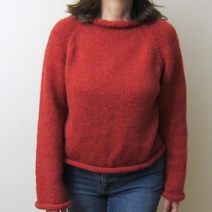 Puede incluir: Un su&eacute;ter de punto color &oacute;xido con cuello redondo y mangas largas. El su&eacute;ter tiene un dobladillo y pu&ntilde;os acanalados. La modelo lleva vaqueros azules. El su&eacute;ter est&aacute; hecho de un material suave y texturizado.