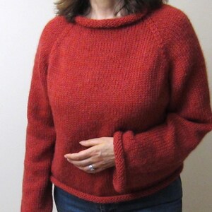 Puede incluir: Un su&eacute;ter rojo tejido con cuello redondo y mangas largas. El su&eacute;ter est&aacute; hecho de un hilo grueso y texturizado y tiene pu&ntilde;os y dobladillo acanalados. El estilo es casual y c&oacute;modo.