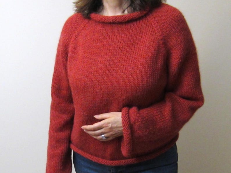 Puede incluir: Un su&eacute;ter rojo tejido con cuello redondo y mangas largas. El su&eacute;ter est&aacute; hecho de un hilo grueso y texturizado y tiene pu&ntilde;os y dobladillo acanalados. El estilo es casual y c&oacute;modo.