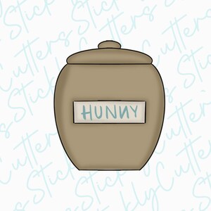 May include: A brown ceramic jar with a lid and a white label that says "Hunny".