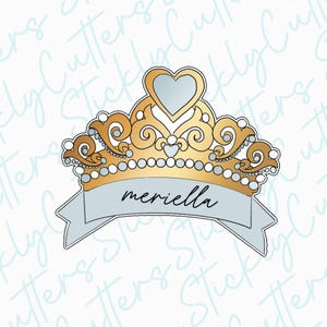 May include: A gold crown with a heart-shaped jewel on top and a white banner with the word "meriella" written in black.