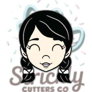May include: A cookie cutter in the shape of a smiling girl's face with black hair in pigtails. The cutter has a light skin tone and closed eyes. The text "Strictly Cutters Co." is visible at the bottom.