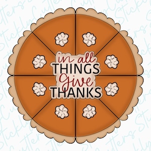 May include: A brown pie crust with a scalloped edge, divided into eight slices. The pie is filled with a brown filling and topped with white decorative swirls. The text "in all THINGS give THANKS" is written in the center of the pie.