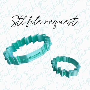 May include: Two turquoise blue plastic cookie cutters, one shaped like a large leaf and the other shaped like a smaller leaf. The larger cutter has the text "beetleguva" on it.