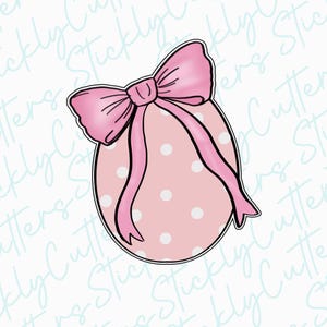 May include: A pink Easter egg with white polka dots and a pink bow. The egg is decorated with a pink ribbon.