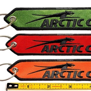 May include: Three keychains with a black and white embroidered Arctic Cat logo. The keychains are green, red, and orange. Each keychain has a silver key ring.