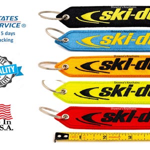 May include: Five colorful keychains with a black "ski-doo" logo on each. The keychains are black, blue, orange, yellow, and red. The keychains are made in the USA.