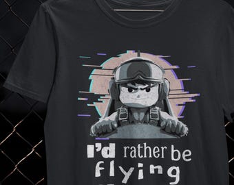May include: Black t-shirt featuring a cartoon pilot in a cockpit with the text "I'd rather be flying PLANES." The pilot is wearing a helmet and goggles. The design includes a retro-style graphic with purple and teal accents.