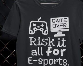May include: Black t-shirt with a white graphic featuring a game controller and computer screen with the words "GAME OVER." Below, the text reads "Risk it all for E-sports."