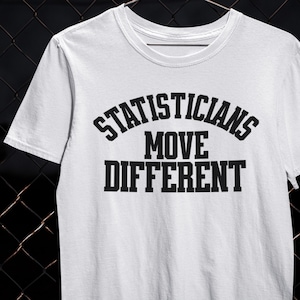 Puede incluir: Camiseta blanca con el texto negro "STATISTICIANS MOVE DIFFERENT". El texto es en negrita y sin serifa. La camiseta tiene cuello redondo y mangas cortas. El texto está dispuesto en tres líneas, con "STATISTICIANS" arqueado sobre "MOVE DIFFERENT".