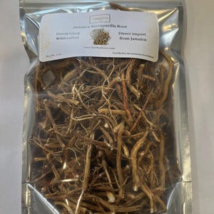 May include: A clear plastic bag filled with dried Jamaica Sarsaparilla Root. The bag has a white label with the text "Jamaica Sarsaparilla Root", "Handpicked Wildcrafted", and "Direct import from Jamaica". The net weight is 2 oz.